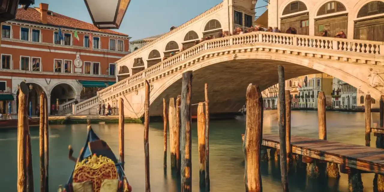 Gondola ferma in un canale di Venezia inverno, con il Ponte di Rialto sullo sfondo.