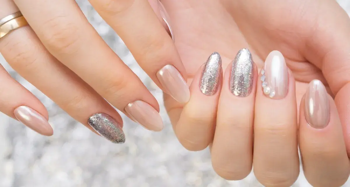 Mani curate con unghie eleganti, un mix di nude perlato e glitter argento, perfetti colori smalto primavera.