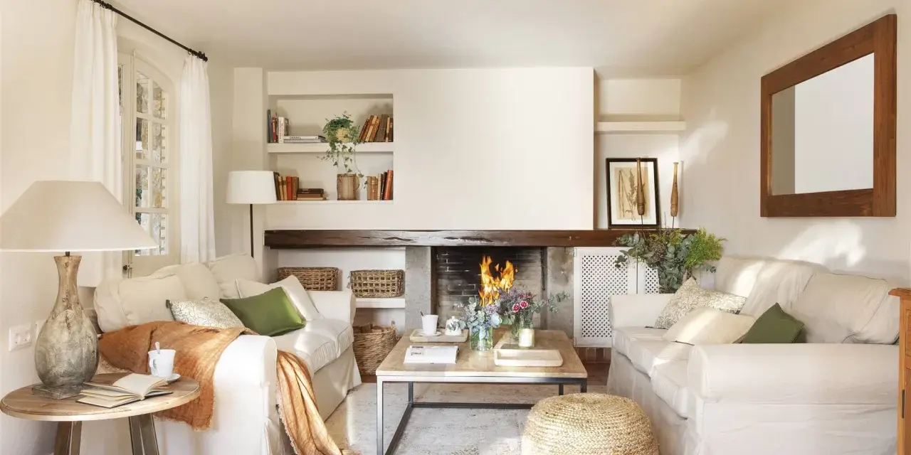 Salón acogedor con chimenea encendida, sofás blancos, mesa de centro de madera y detalles decorativos.