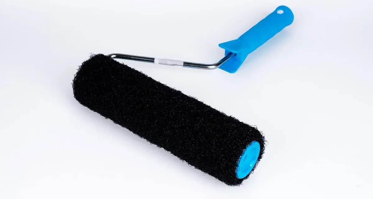 En svart roller med blått handtag, perfekt för att applicera rullspackel jämnt på väggar.