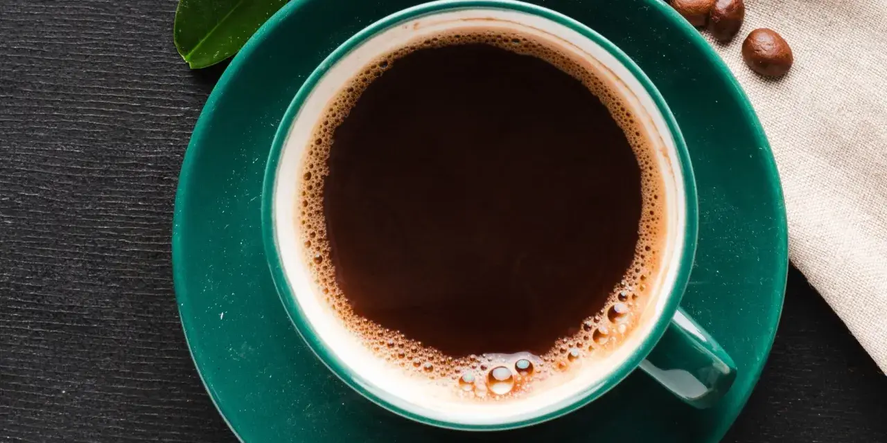 Aromatic coffee in a green cup, next to chocolate and beans. Czy kawa podnosi kortyzol? This morning brew might be the answer.