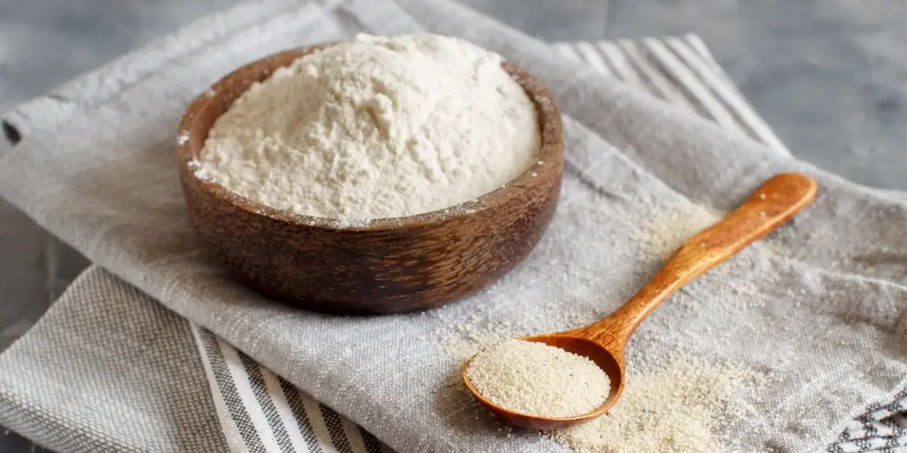 Mąka gryczana w drewnianej misce i na łyżce. Czy mąka gryczana ma gluten? Nie, jest bezglutenowa.