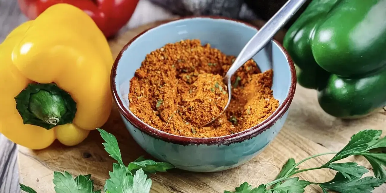 Schüssel mit Gewürzmischung zum **pul biber selbst mischen**. Bunte Paprika und Petersilie liegen daneben.