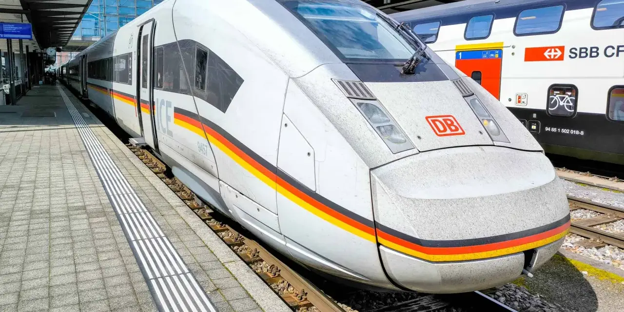 ICE train with German flag colors at a station, ready for a journey between Germany and Switzerland.