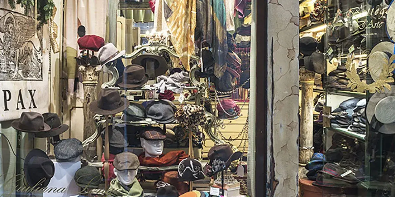 Vetrina di negozi Venezia con cappelli eleganti e sciarpe colorate, un'esplosione di stile per ogni occasione.