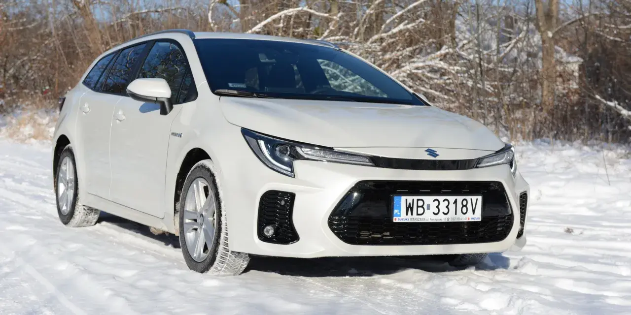 Biały Suzuki Swace Hybrid na śniegu, gotowy na zimowe wyzwania.