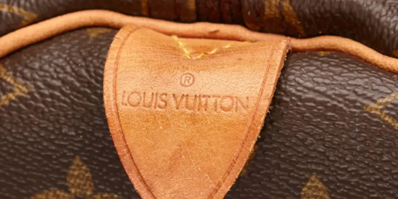 Etichetta in pelle con logo Louis Vuitton, un dettaglio iconico che evoca la maestria della fabbrica Louis Vuitton.