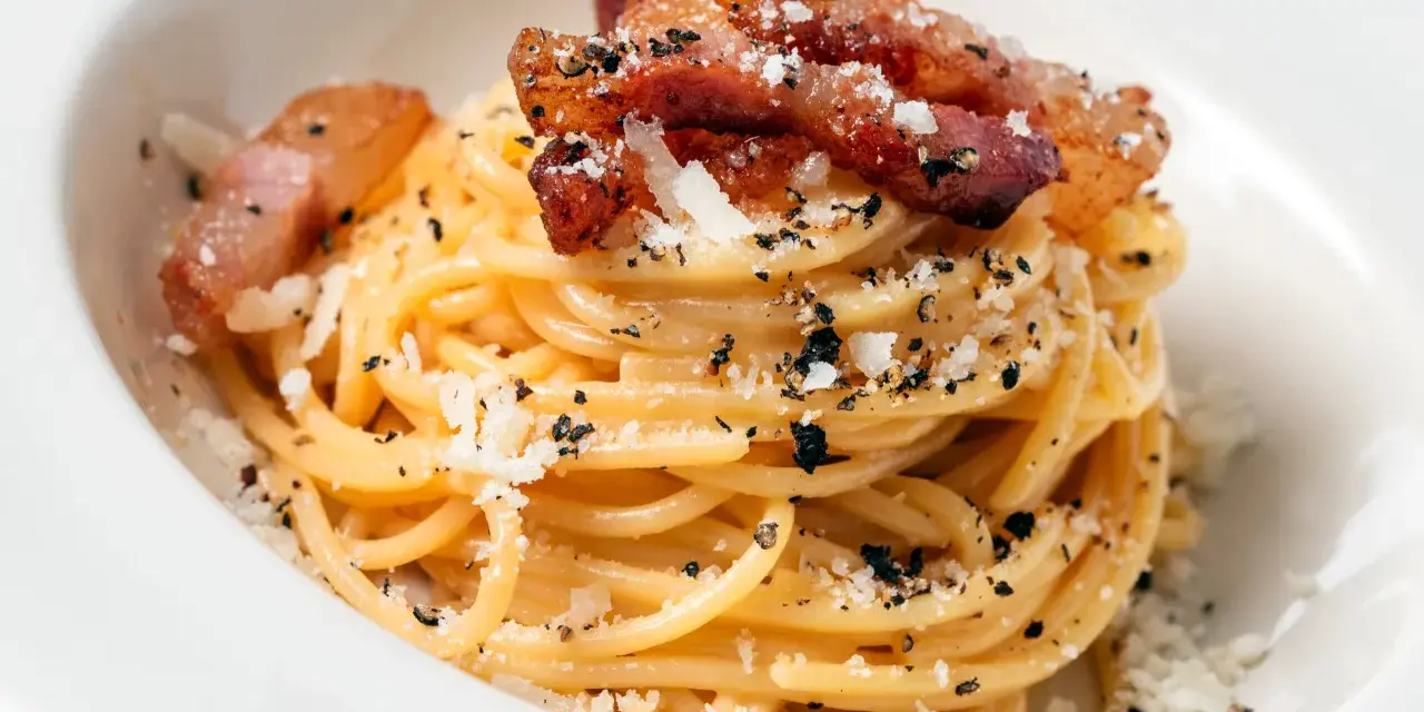 Spaghetti carbonara z chrupiącym guanciale, posypane parmezanem i czarnym pieprzem. To właśnie guanciale nadaje autentyczny smak.