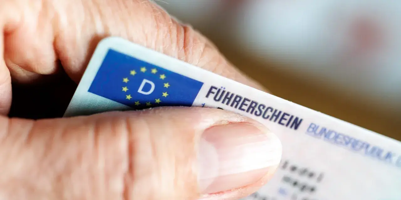 Nahaufnahme eines Führerscheins, der von einer Hand gehalten wird. Die Person könnte versucht sein, trotz Fahrverbot zu fahren.