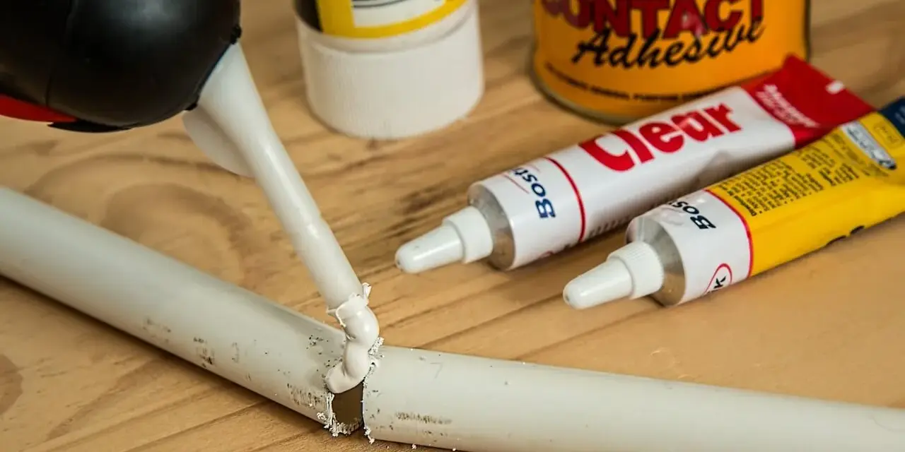 Klej w tubce i pistolet do klejenia na drewnianym blacie. Zastanawiasz się, czym usunąć klej super glue z mebli?