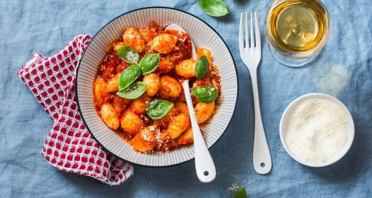Pyszne gnocchi w sosie pomidorowym, posypane parmezanem. Idealne z kieliszkiem białego wina.