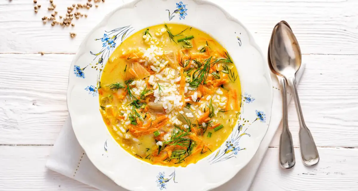 Aromaticzna zupa koperkowa z ryżem, marchewką i kawałkami kurczaka, udekorowana świeżym koperkiem.