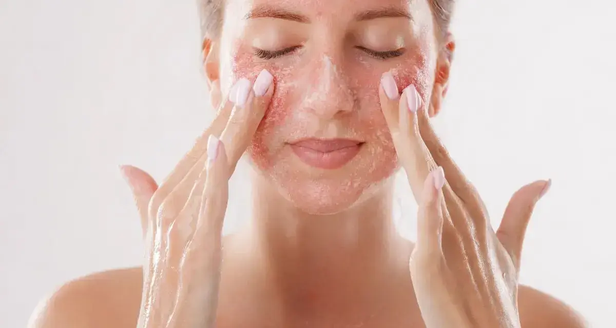 Kobieta z zamkniętymi oczami delikatnie masuje twarz, aplikując produkt z drobinkami. To może być skuteczny retinol na zaskórniki, który odnawia skórę.