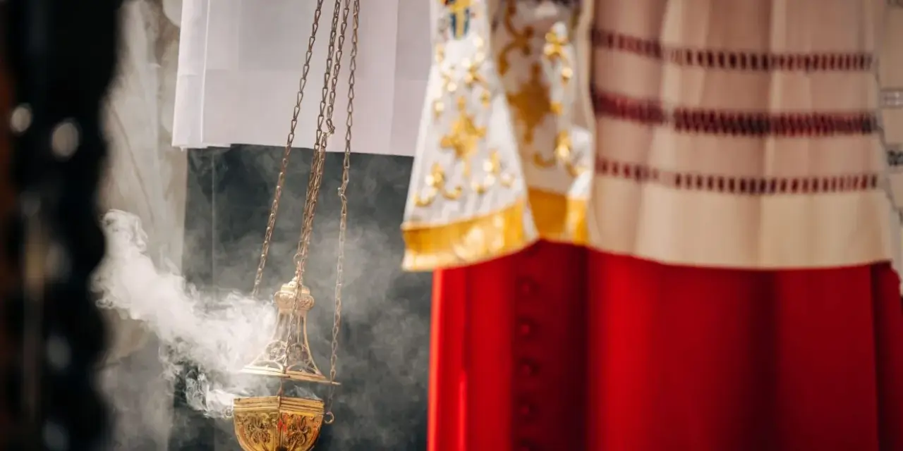Złota kadzielnica unosi dym podczas uroczystości. W tle widać szaty liturgiczne, przypominające o święta nakazane.