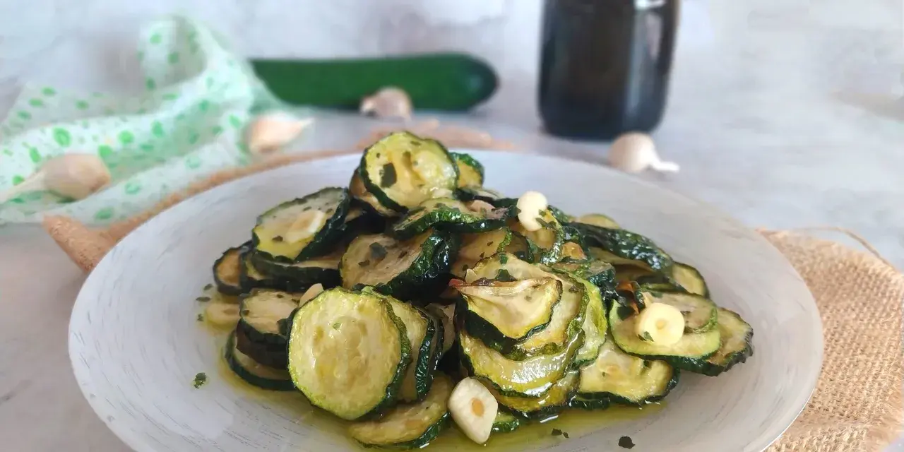 Piatto di zucchine alla scapece, fette sottili condite con olio, aglio e prezzemolo.