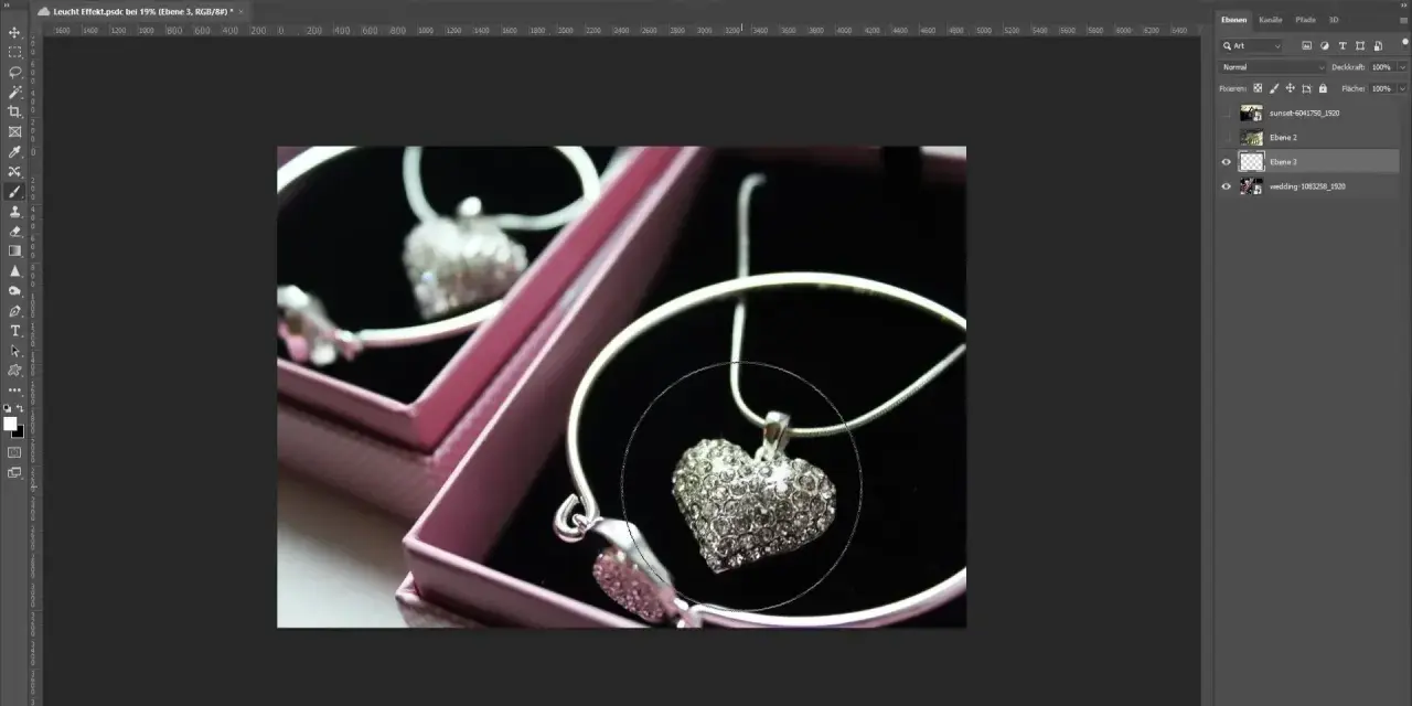 Un collier en forme de cœur orné de strass, dans une boîte rose. Un effet lumière Photoshop est appliqué pour le faire scintiller.