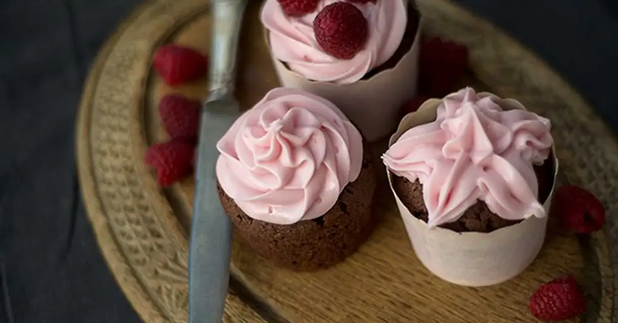 Tre chokladcupcakes med rosa frosting och hallon, redo att avnjutas. Ett perfekt cupcakes recept för alla tillfällen.