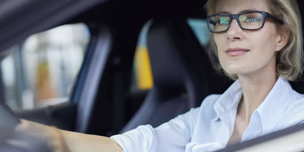 Frau mit Brille fährt Auto. Ohne Brille fahren ohne Brille Strafe.