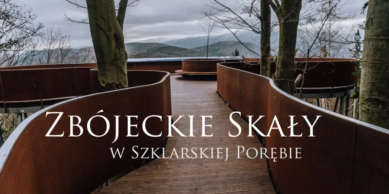 Złoty widok ze ścieżki w koronach drzew w Szklarskiej Porębie. Drewniana kładka z rdzawo-brązowymi balustradami wije się wśród drzew, prowadząc do punktu widokowego.