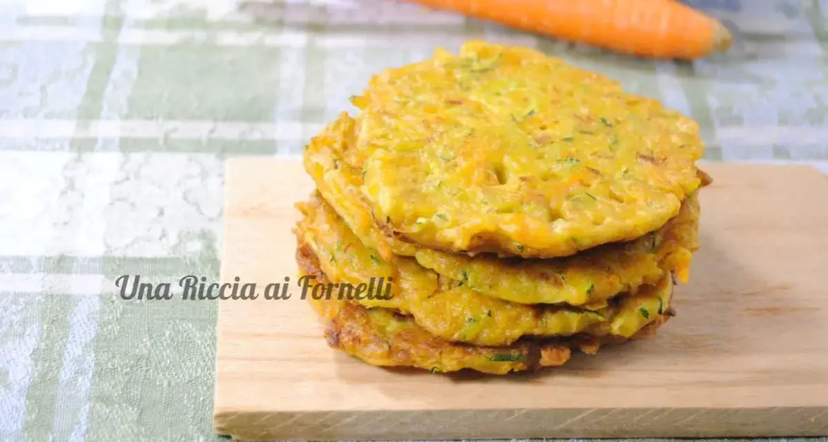Pancakes dorati di frittata con farina di ceci, serviti su un tagliere di legno, con carote sullo sfondo.