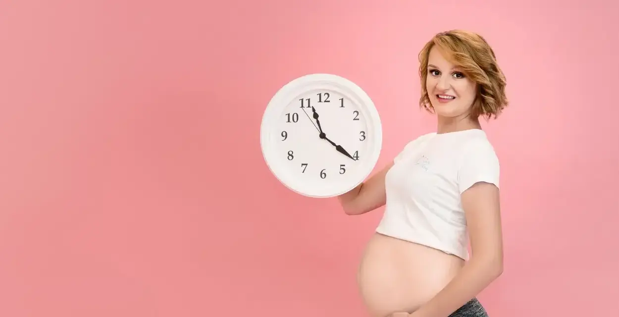 Czekasz na poród? Zegar w rękach ciężarnej sugeruje, jak przyspieszyć poród, choć to tylko symboliczne pytanie.