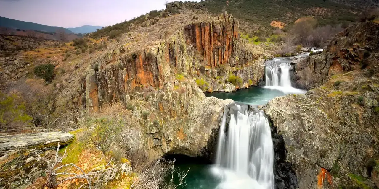Cascadas en el río Guadalajara, rodeadas de rocas rojizas y vegetación otoñal.