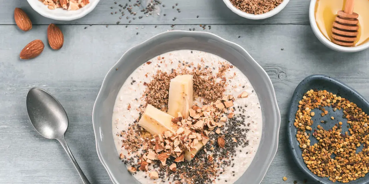 Avena con plátano, almendras picadas, chía y miel, rodeada de ingredientes.