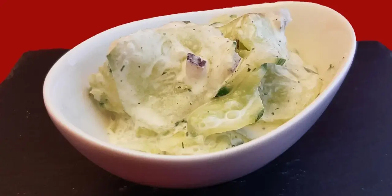 Salade fraîche de concombre à la crème, parsemée d'herbes fines. Un délice léger et savoureux.