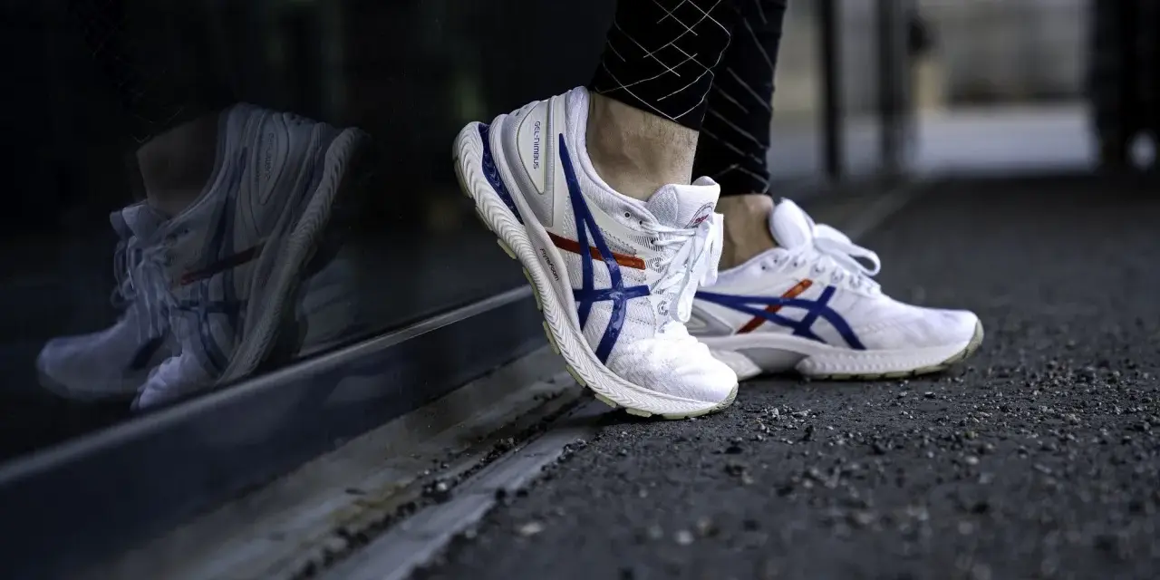 Vita Asics-skor med blå och röda detaljer, perfekt för löpning. Kolla in vår asics storleksguide för rätt passform.