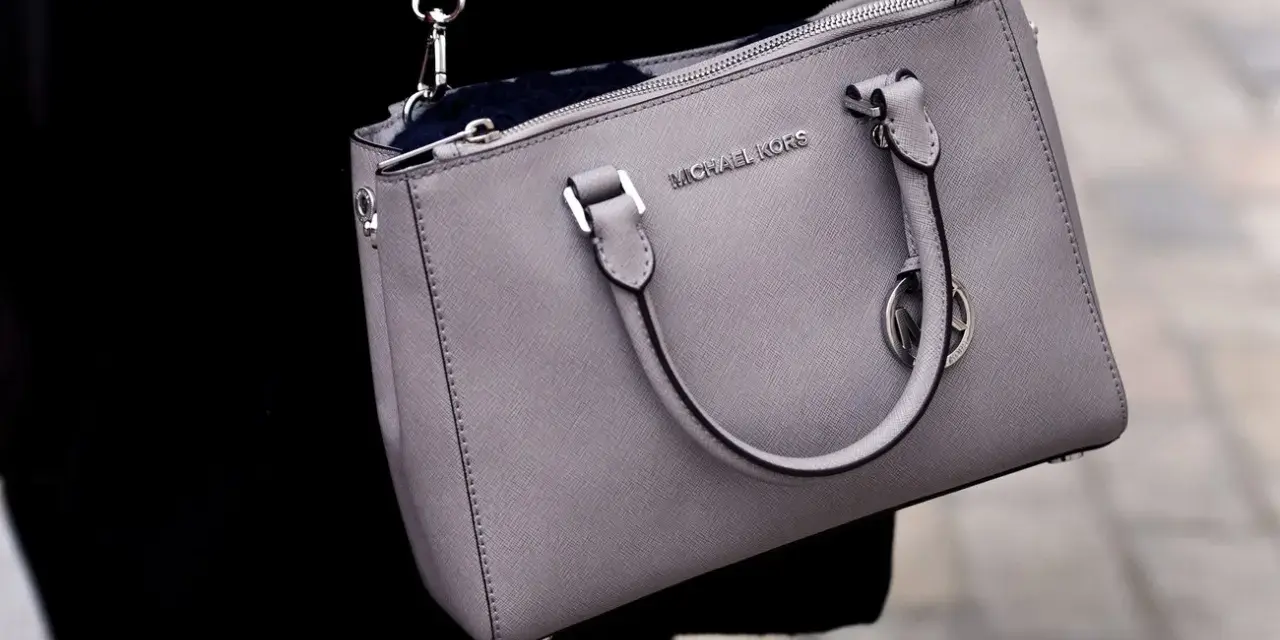 Szara torebka Michael Kors, znanej firmy z luksusowymi akcesoriami, z widocznym logo.
