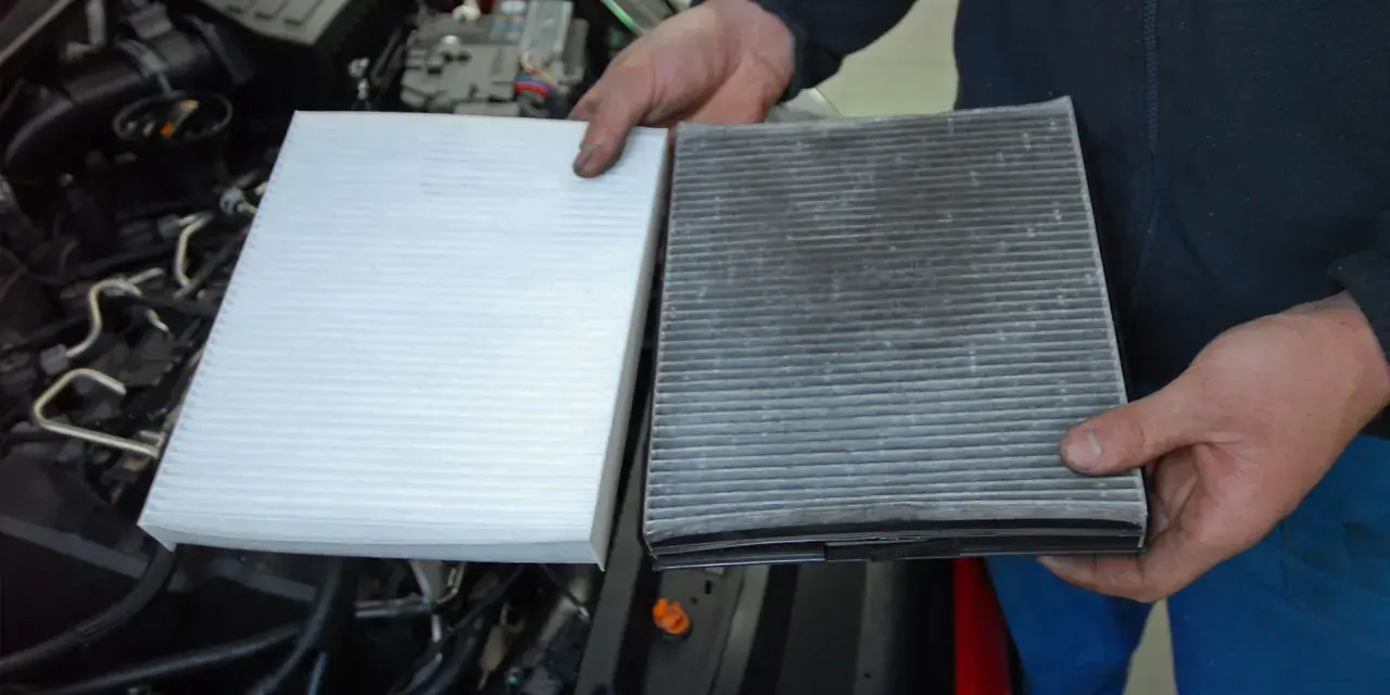 Hands hold a new white air filter next to a dirty, used one, ready to replace air filter in car.