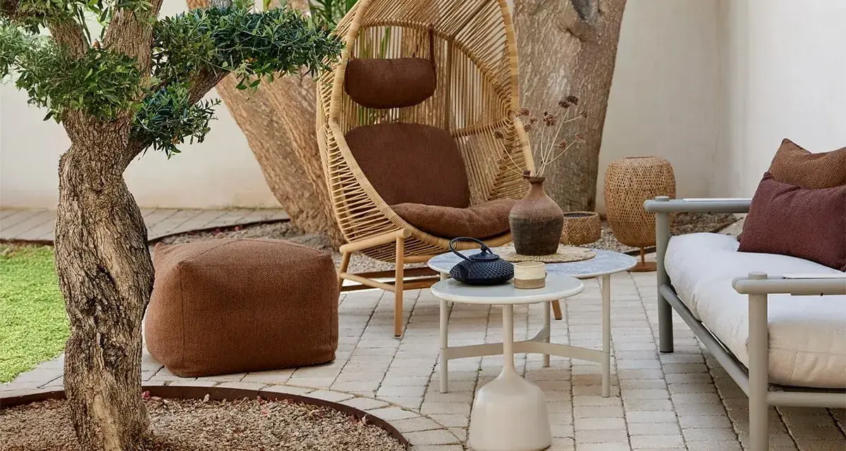 Gemütlich die **terrasse gestalten**: Rattan-Sessel, bequeme Sitzbank, Pouf und kleine Tische laden zum Verweilen ein.