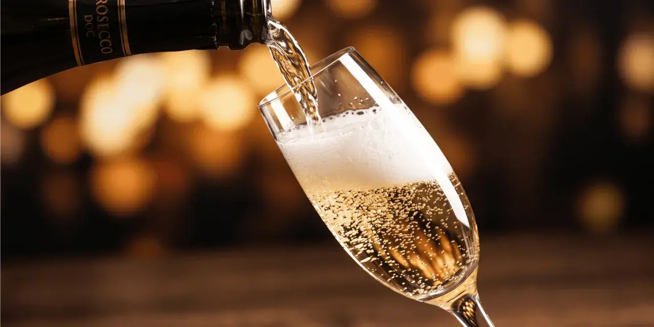 Bąbelki musującego prosecco wypełniają kieliszek, gdy jest nalewane z butelki. To jest właśnie to, co to jest prosecco – włoskie wino musujące.
