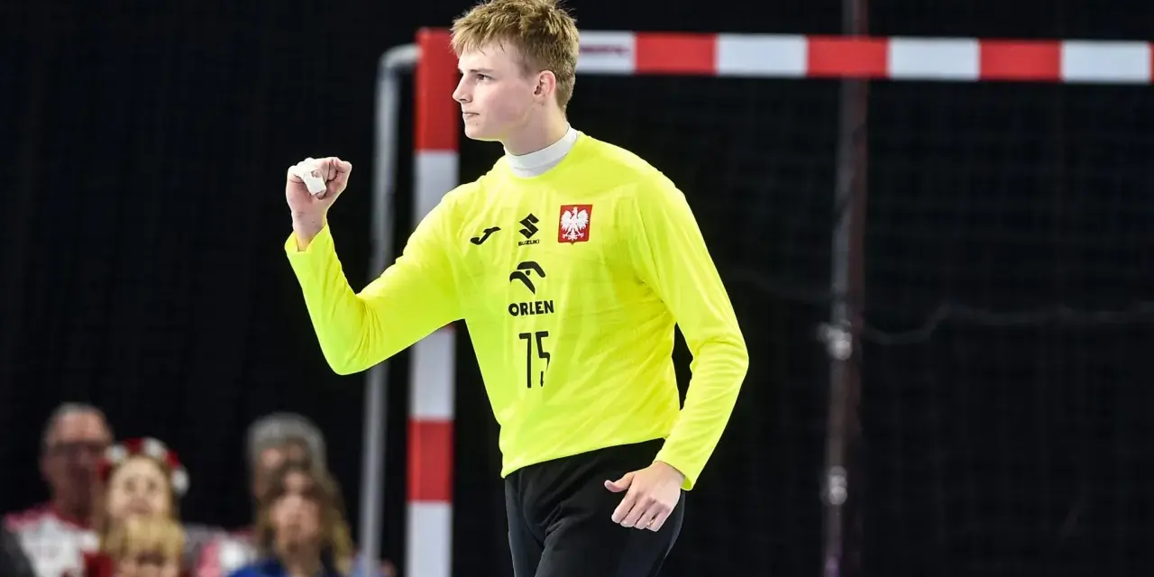 Marcel Jastrzębski, młody bramkarz w żółtej koszulce z orłem, zaciśniętą pięścią świętuje udaną interwencję.