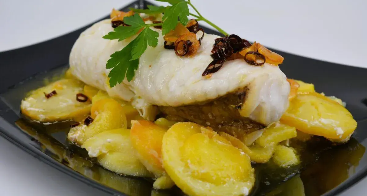 Rape con patatas, un plato delicioso con pescado blanco tierno y patatas doradas, decorado con perejil fresco y crujientes trozos de ajo frito.