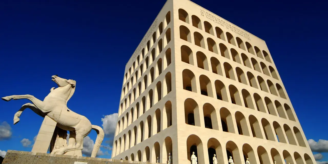 Le palais de la civilisation italienne, monument emblématique, se dresse fièrement sous un ciel bleu éclatant, avec une statue de cheval en avant-plan.