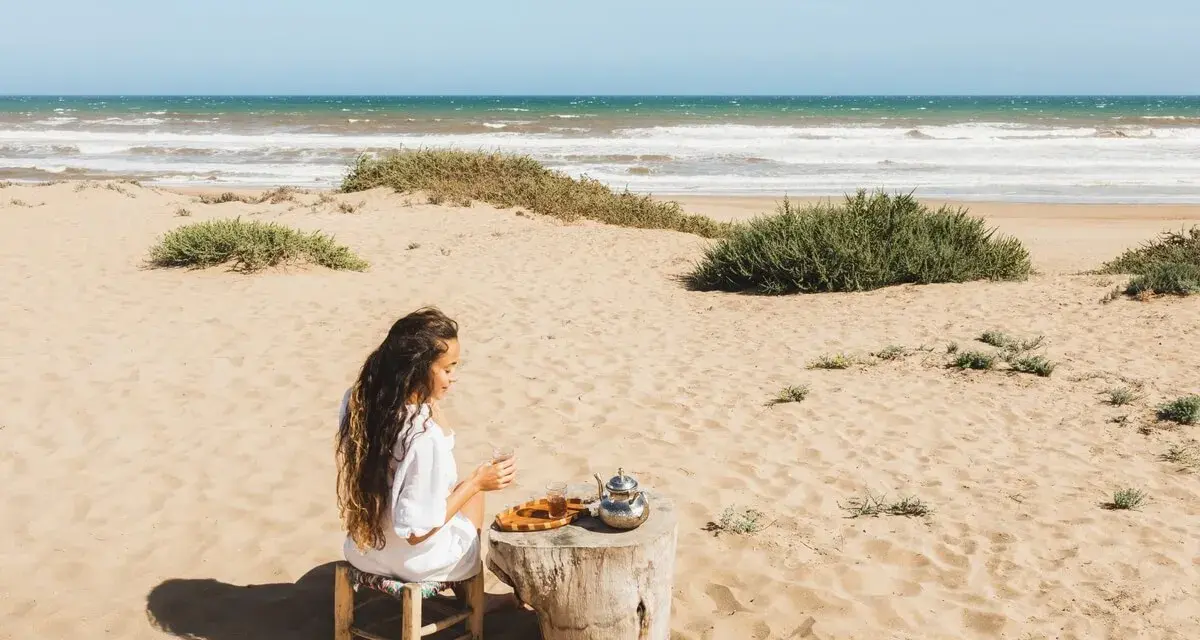 Kobieta pije herbatę na plaży, delektując się spokojem. To jedno z tunezja najpiękniejsze miejsca, gdzie czas płynie wolniej.