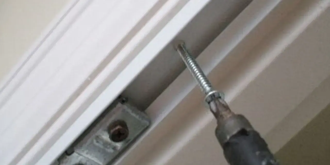 Screwdriver installing a bracket for how to install bifold doors.