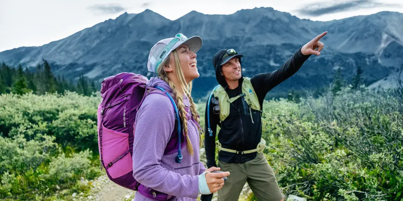 Deux randonneurs s'émerveillent devant un panorama de amm montagne. L'un d'eux pointe du doigt un sommet lointain.