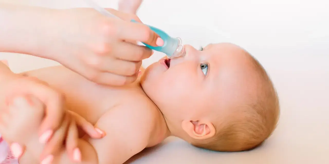 Manos cuidadosas realizan lavado nasal a un bebé.