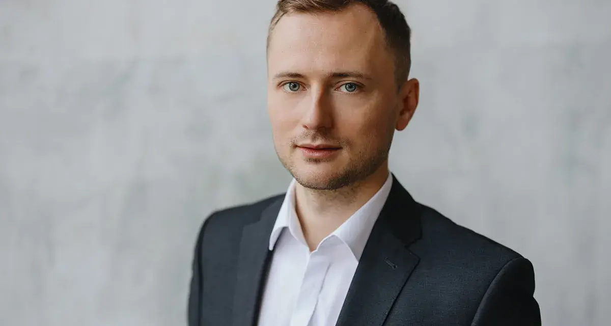 Mężczyzna w garniturze i białej koszuli, idealny przykład, jak zrobić zdjęcie biznesowe w domu.