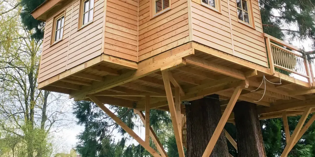 Ein wunderschönes Baumhaus, das auf zwei alten Bäumen gebaut wurde. Die Holzkonstruktion ist solide und einladend.
