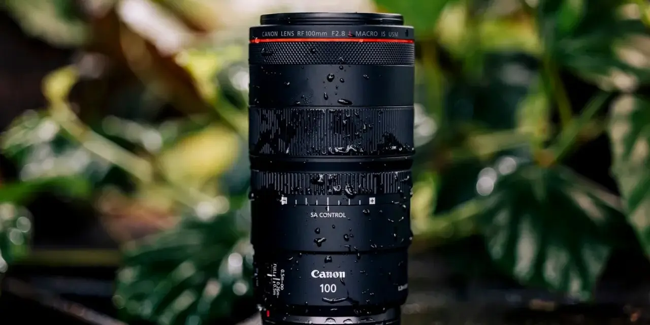 Objectif Canon RF 100mm f/2.8 Macro IS USM, couvert de gouttes d'eau, prêt pour un test en extérieur.