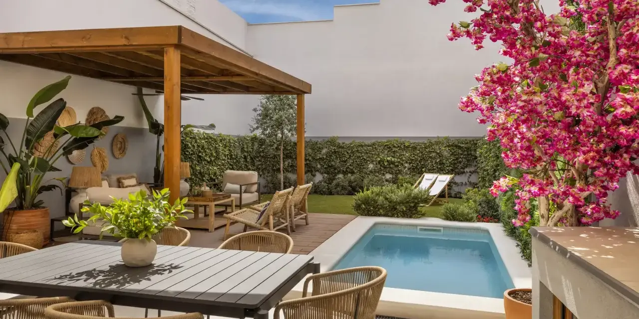 Un patio moderno con piscina, pérgola de madera, zona de estar y comedor exterior. Ideas para decorar un patio con piscina y crear un oasis de relax.