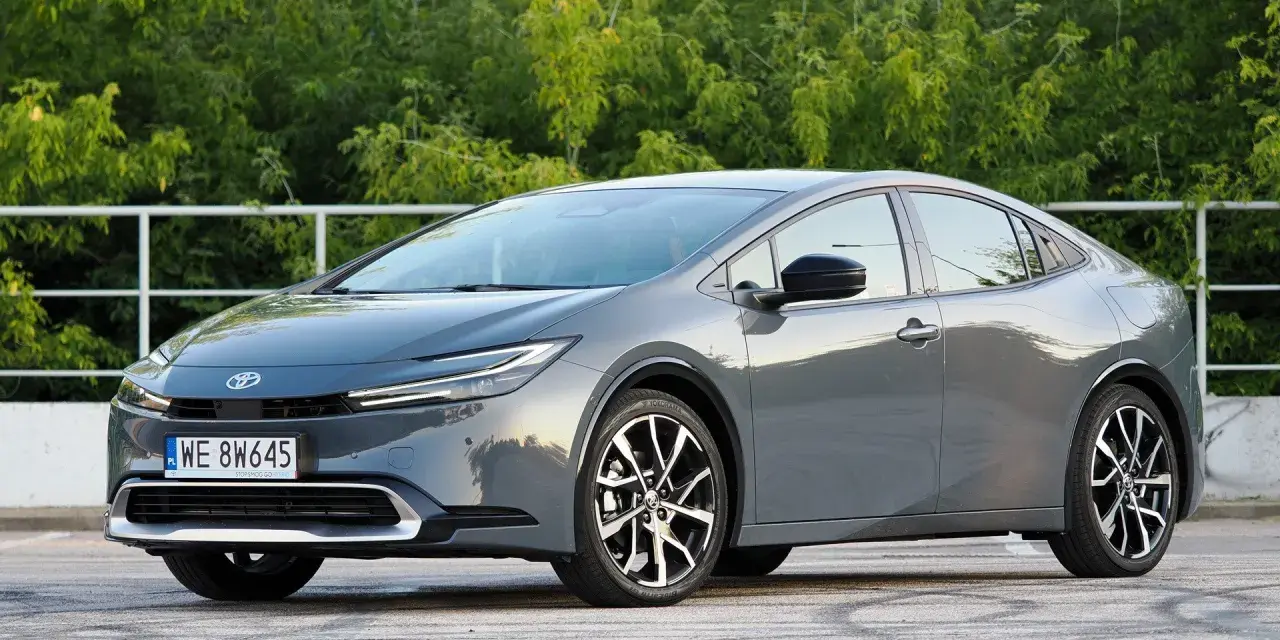 Szary Toyota Prius hybryda na tle zieleni. Zastanawiasz się, ile pali Toyota Prius hybryda? Ten model zachwyca niskim spalaniem.