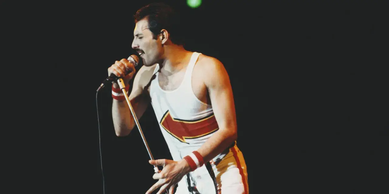 Freddie Mercury, jeden z najlepsi muzycy wszechczasów, śpiewa do mikrofonu na koncercie.