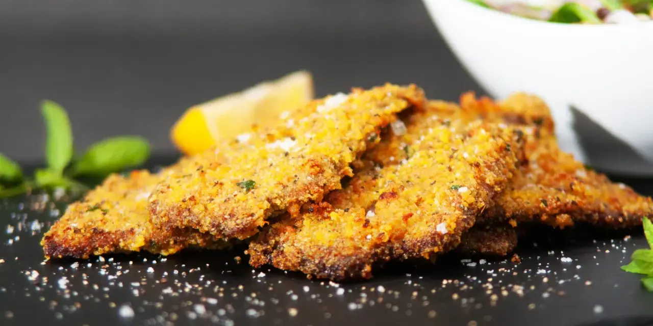 Cotoletta alla palermitana dorata e croccante, guarnita con limone e menta.
