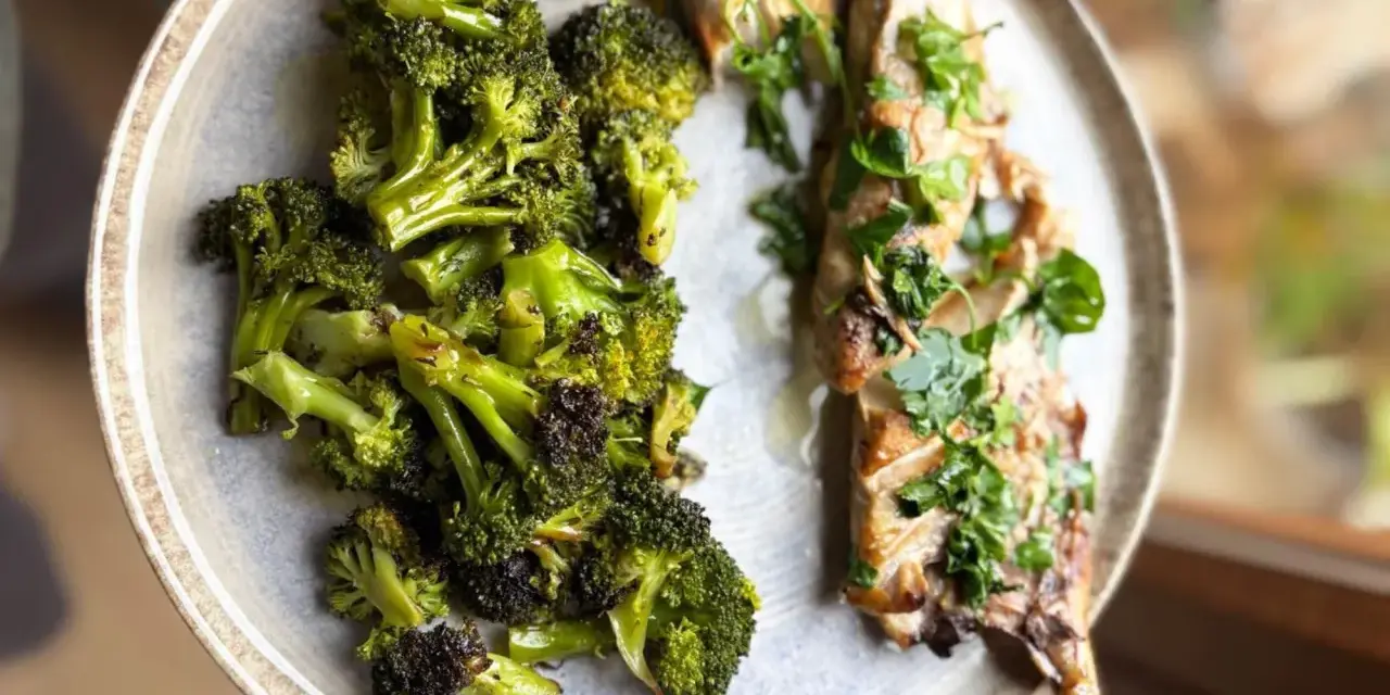 Brocoli al horno, tierno y dorado, junto a un filete de pescado con hierbas frescas.