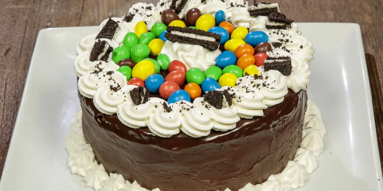 Torta al cioccolato con panna, caramelle colorate e biscotti Oreo, un'esplosione di gusto per torte di compleanno particolari.