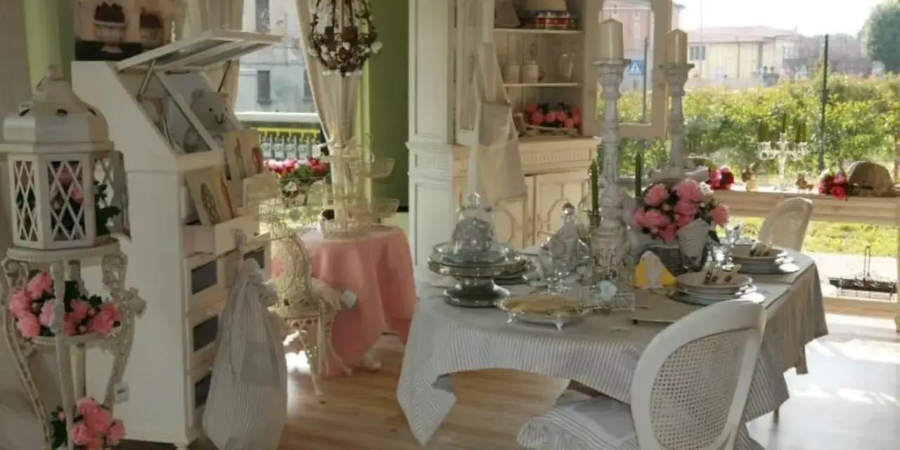 Un tavolo apparecchiato in **stile provenzale francese**, con sedie bianche, candelabri e fiori rosa.